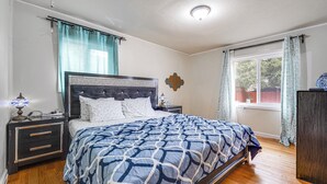 A bedroom with a bed, nightstands, a window with curtains, and a wooden floor.