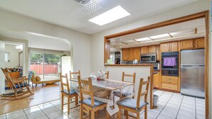 A spacious kitchen with wooden cabinets, a stainless steel refrigerator, and a dining area with a table and chairs.