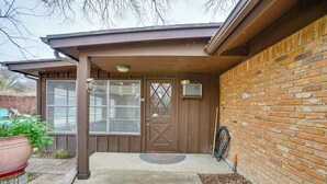 A brown wooden house with a large front door, a window, and a brick wall. - Karaoke Ready! Fort Worth Area Home (Aledo)