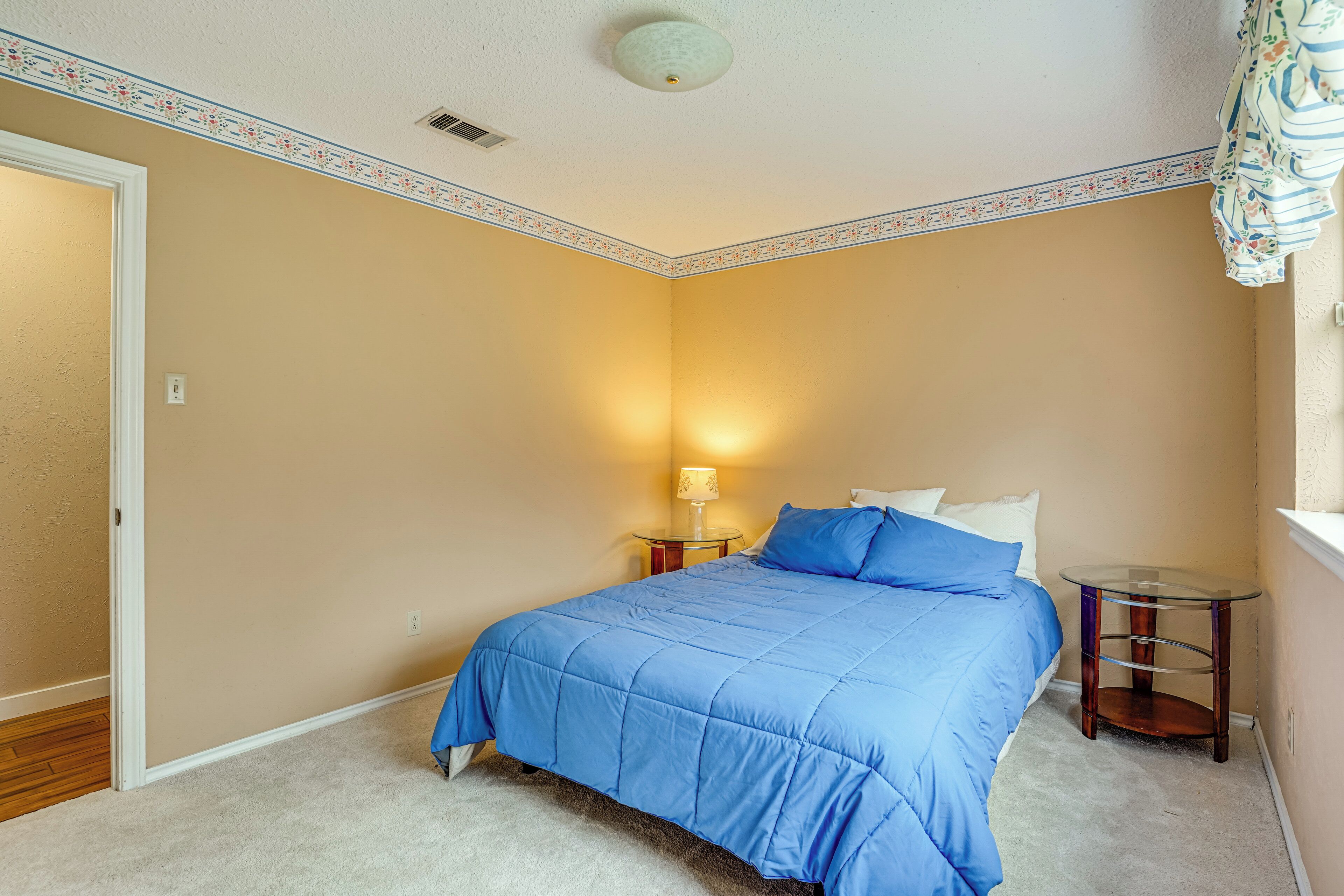 A bedroom with a bed, a nightstand, and a lamp.