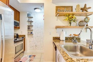 A modern kitchen with stainless steel appliances, wooden cabinets, and a granite countertop.