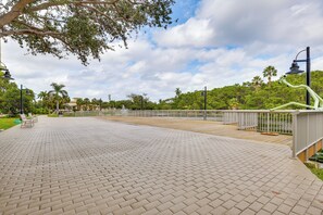 Un vialetto lastricato con panchine, una ringhiera e vista su un parco con alberi e un edificio sullo sfondo.