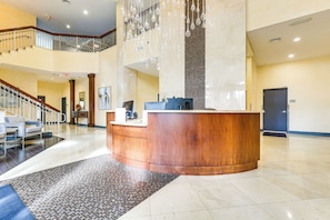 Un'ampia hall con una reception, una scala e un soffitto alto con lampade a sospensione.