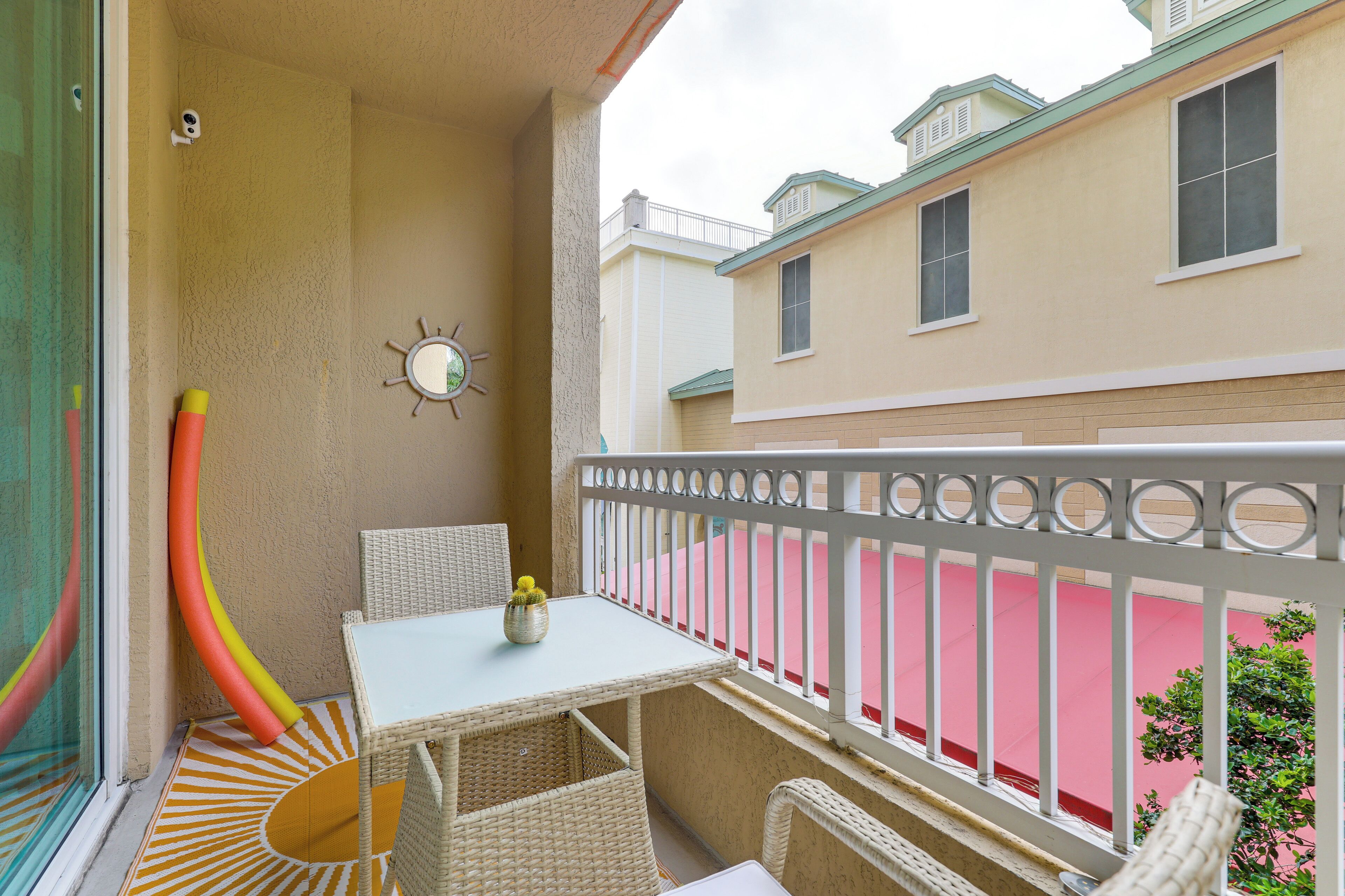 A balcony with wicker furniture, a small table, and a decorative mirror.