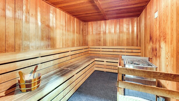 Una sauna de madera con bancos y una rejilla metálica.