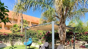 A well-maintained outdoor area with artificial grass, lounge chairs, and a pergola providing shade. - CT 362 AL - Primera Linea - Vera Playa  (Vera)