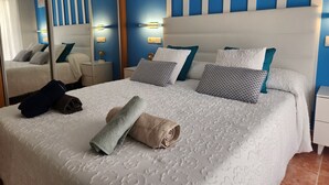 A neatly made bed with a white and grey patterned bedspread, two pillows with a grey and white geometric pattern, and a rolled-up beige towel on the bed. - CT 362 AL - Primera Linea - Vera Playa  (Vera)