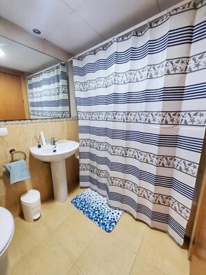 A bathroom with a sink, toilet, and a shower curtain with a striped pattern. - CT 362 AL - Primera Linea - Vera Playa  (Vera)