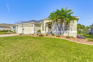 A single-story house with a garage, a well-maintained lawn, and a palm tree. - Near Golf Courses: Home w/ Sunroom in The Villages (The Villages)