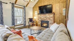 A cozy living room with a fireplace, a large window, and a comfortable seating area. - Walk to Hideout Slopes: Home w/ Game Room! (Lake Ariel)