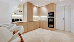 Une cuisine moderne avec des meubles en bois, un four encastré et un plan de travail blanc.