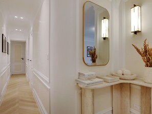 Stunning hallway with a large mirror, console table, and elegant door at the end.