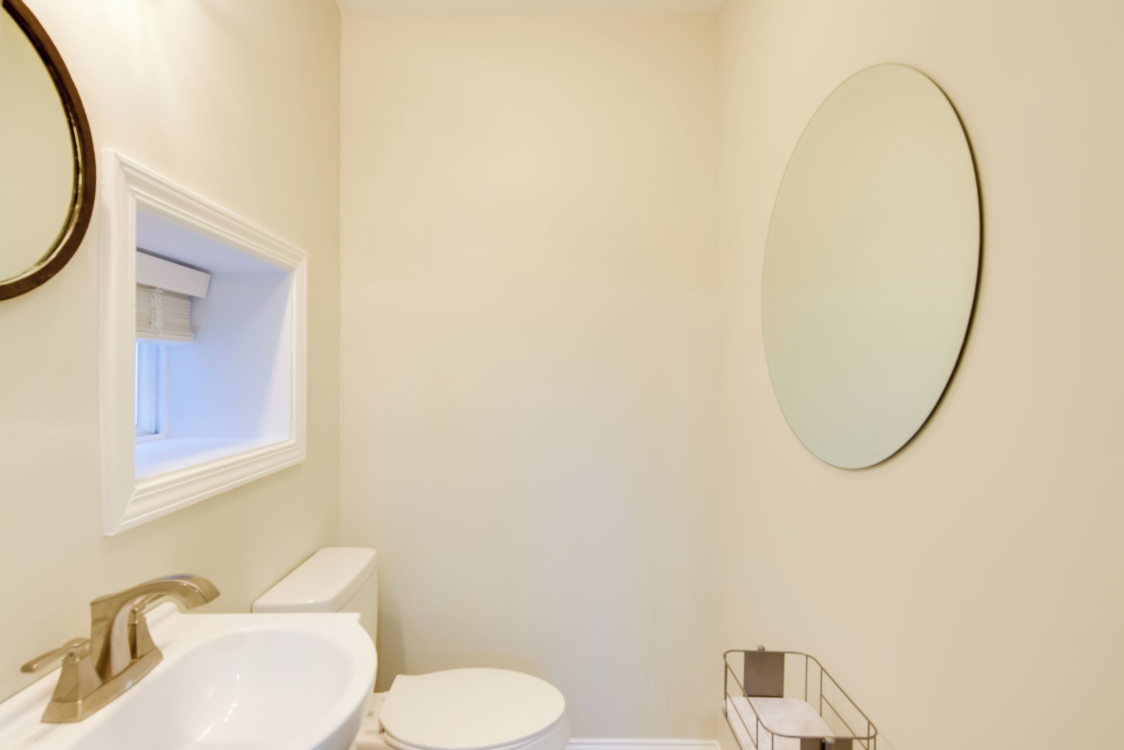 A bathroom with a white sink, toilet, and a large mirror.