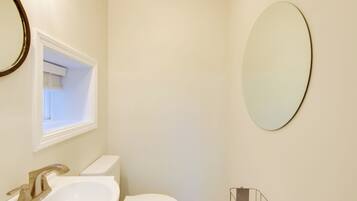 A bathroom with a white sink, toilet, and a large mirror.