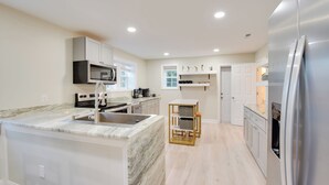 Een moderne keuken met een marmeren eiland, roestvrijstalen apparatuur en licht houten vloeren.