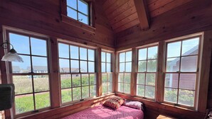 A wooden cabin room with a bed, large windows, and a desk. - Unique Coastal Retreat in Exclusive Condo Complex (2392) (Truro)