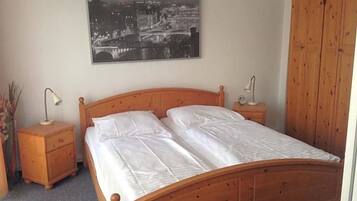 Een slaapkamer met een houten bed, twee nachtkastjes, een wandeling stadsgezicht aan de muur.