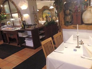 A dining area with a table set for two, a small bar area, and a decorative backdrop.