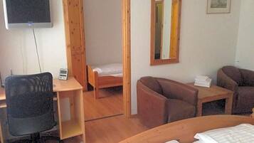 Een kamer met een bed, bureau, stoel, bank, televisie en spiegel.