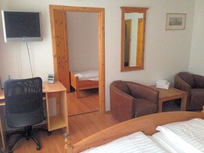 A room with a bed, a desk, a chair, a sofa, a TV, and a mirror.
