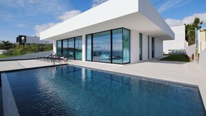 A modern house with a swimming pool, large glass windows, and a white exterior.