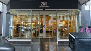 Un edificio moderno con fachada de vidrio, número 250, y una señal que indica la calle Elizabeth.