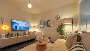 Una sala de estar moderna con una televisión de pantalla plana, un sofá, una mesa de centro y una lámpara.