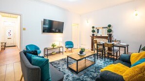 Ett modernt vardagsrum med en platt-TV, ett soffbord och sittmöbler, inklusive en soffa och fåtöljer.