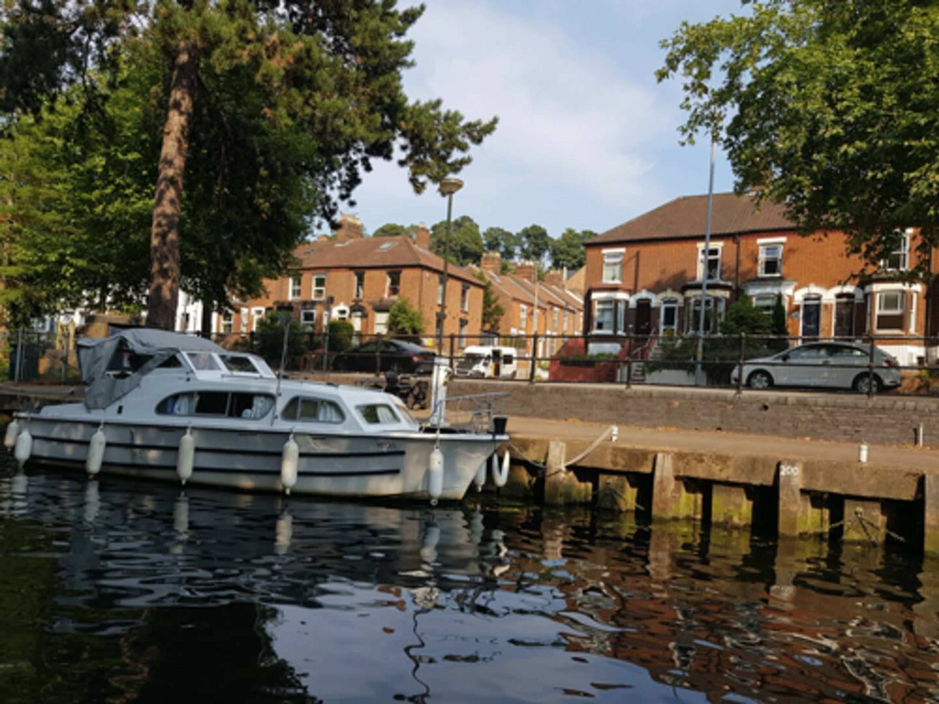 A boat docked at a pier with residential buildings in the background.