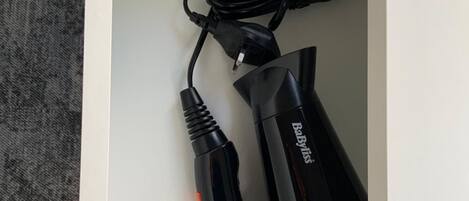 A white drawer containing a black hair clipper with a cord.