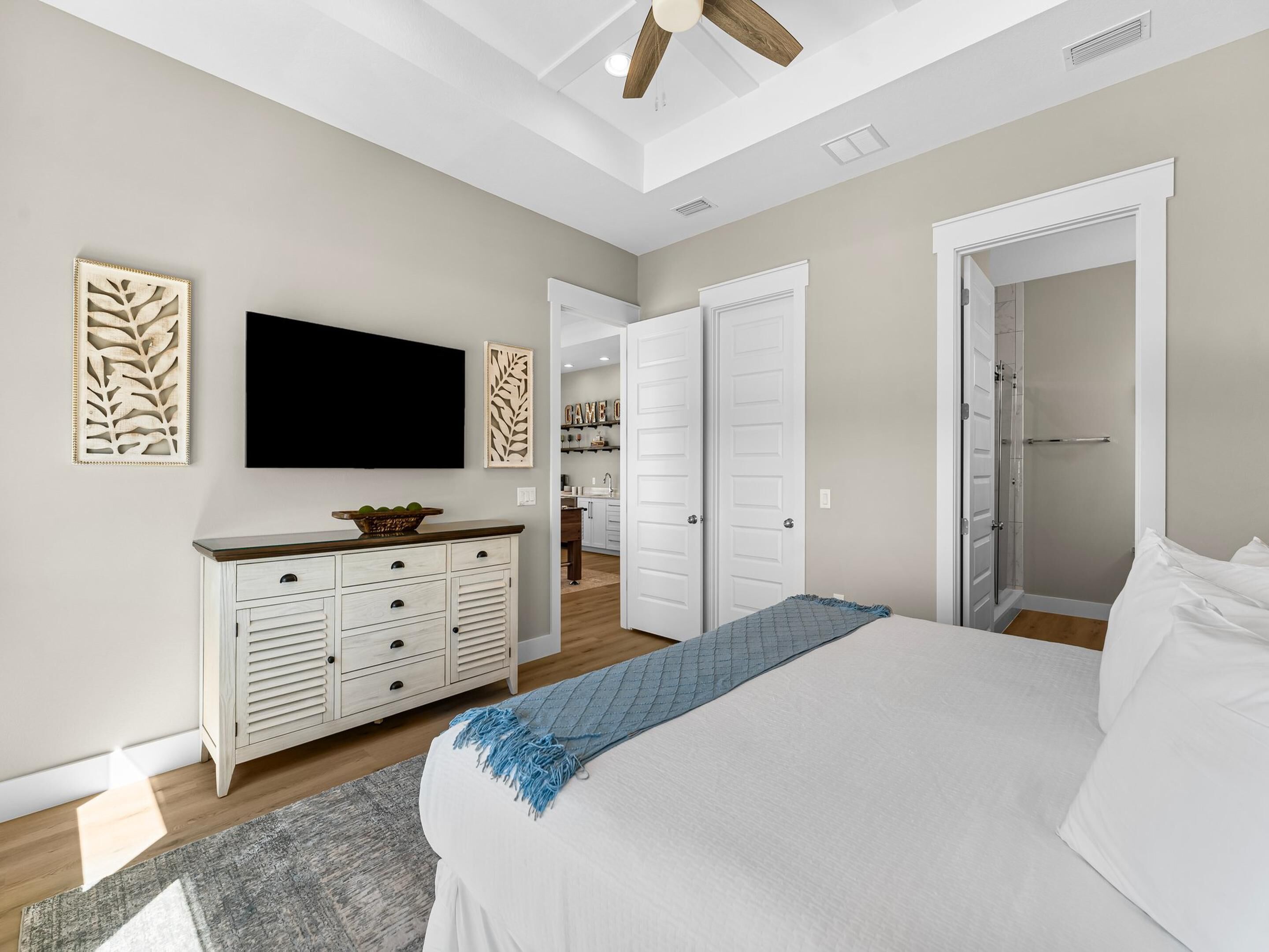 A bedroom with a bed, a TV, a dresser, and a walk-in closet.