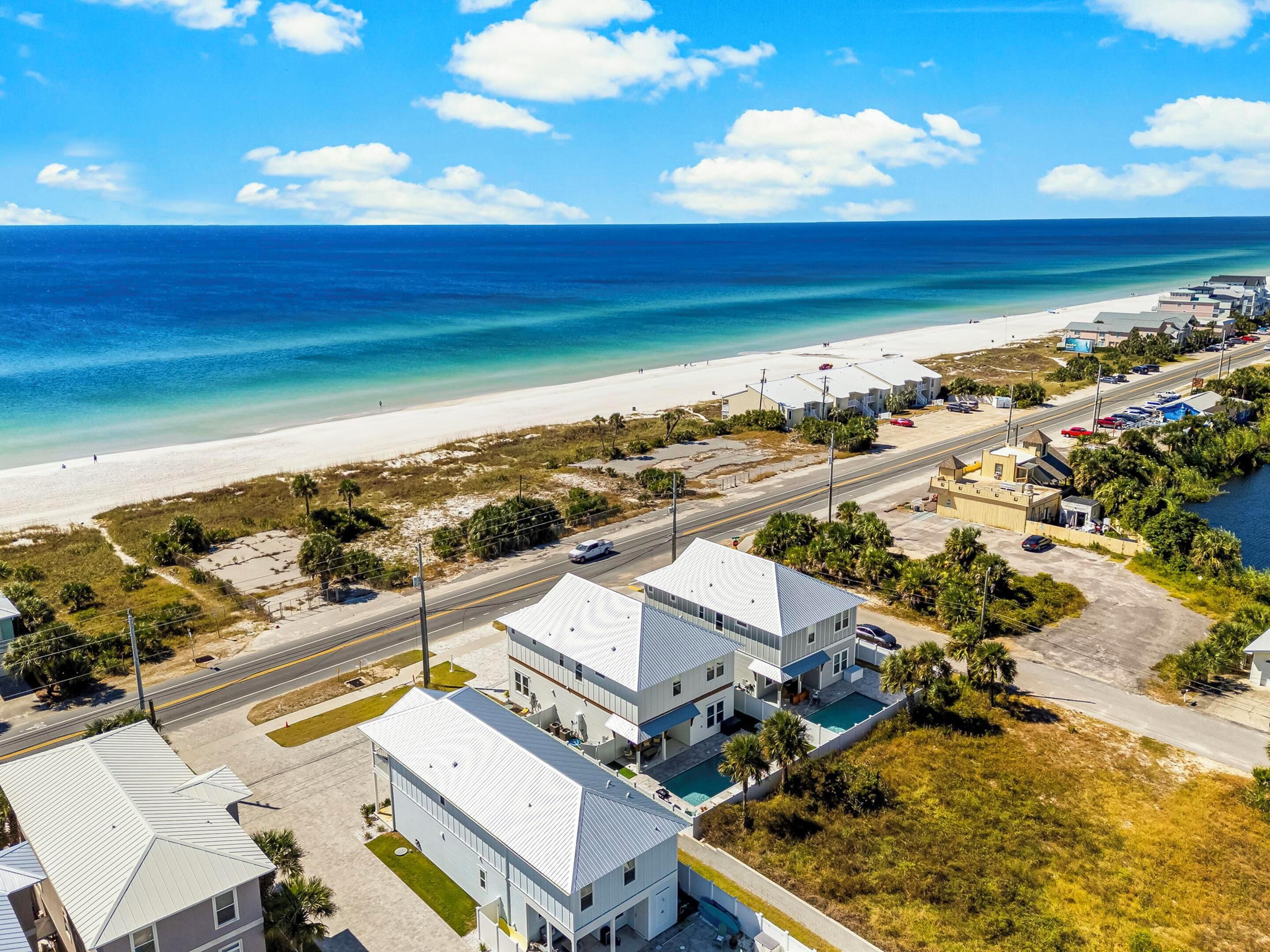 Zona costera con playa, una carretera y varios edificios, incluyendo un hotel con piscina.