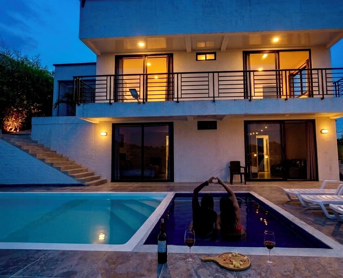 Una casa moderna de dos pisos con piscina, un balcón y una escalera que lleva al nivel superior.