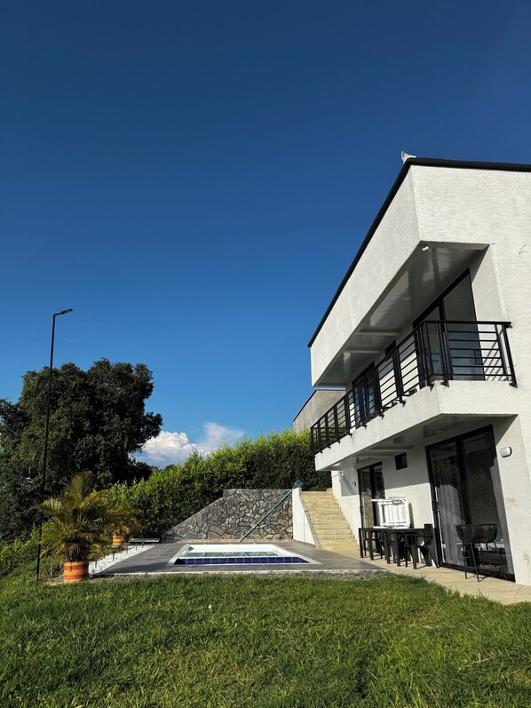 A modern two-story house with a stone staircase leading to a balcony.