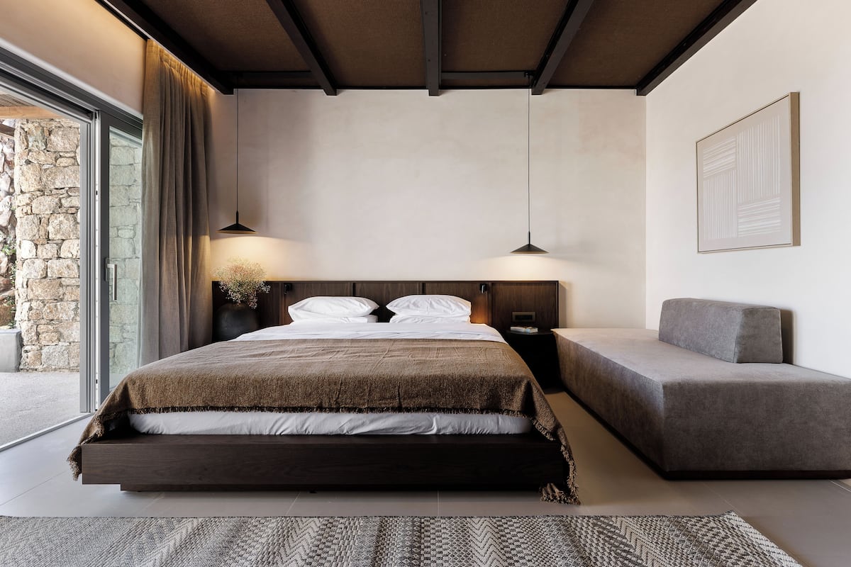 Een moderne slaapkamer met een groot bed, een bank en een stenen muur.
