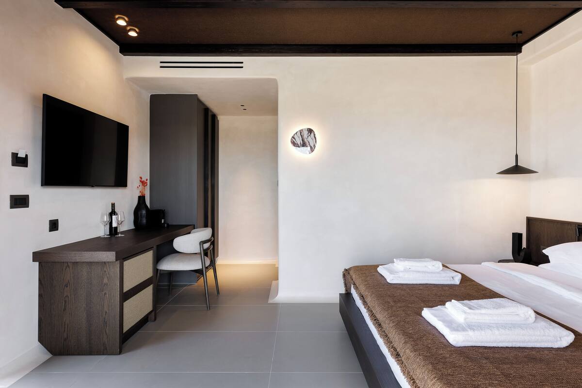 Een moderne hotelkamer met een groot bed, een bureau met een flatscreen-tv en een zithoek met een stoel.