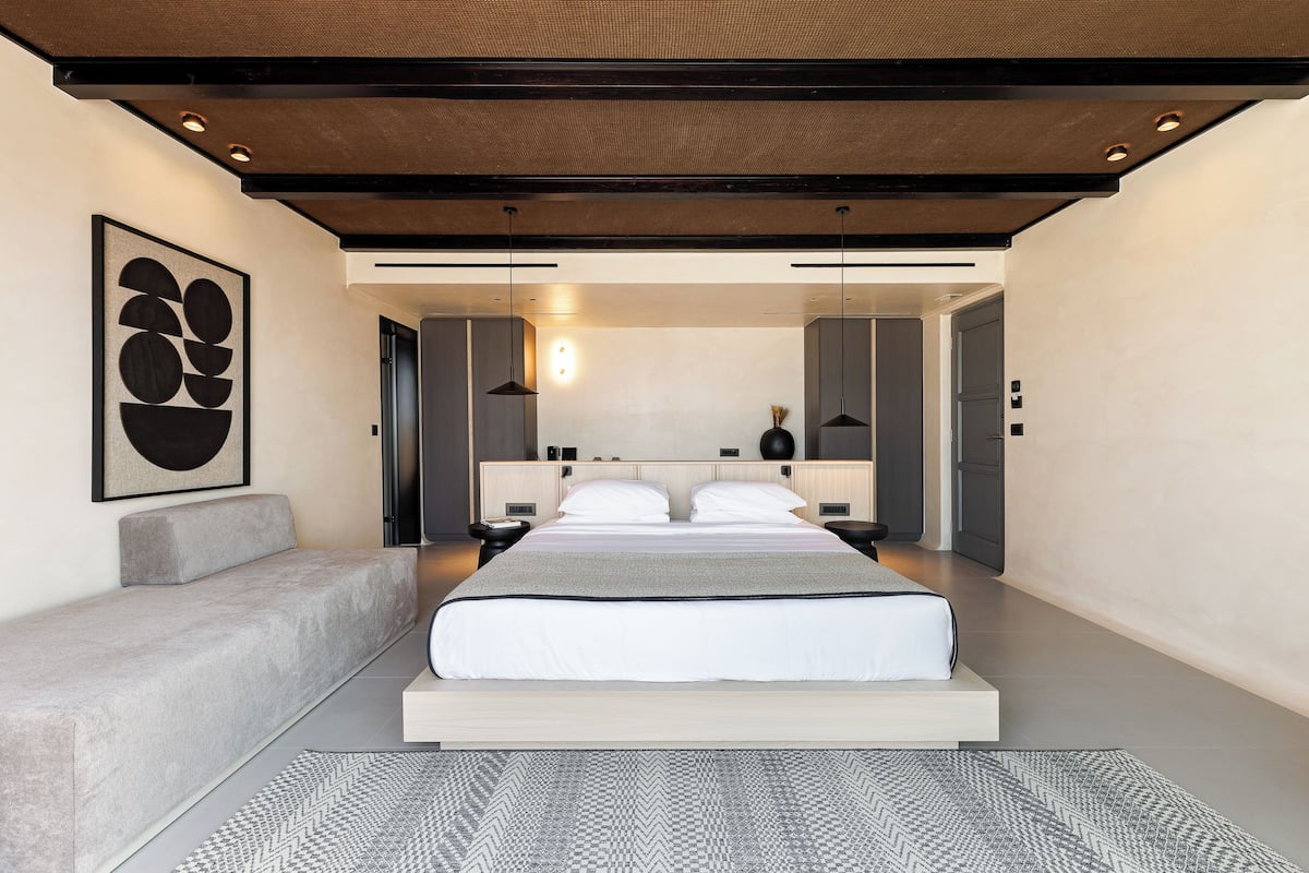 Een moderne slaapkamer met een groot bed, een bank en een kunstwerk aan de muur.