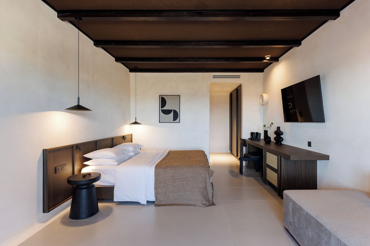 Een moderne slaapkamer met een bed, nachtkastje en een werkplek met een stoel.
