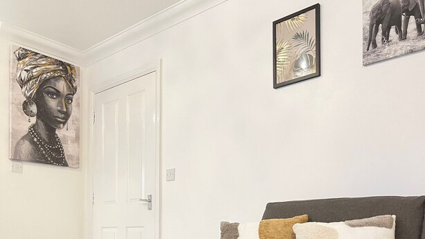 A living room with a grey sofa, a wicker fruit basket, and two framed pictures on the wall. - The Madison Apartment (Dagenham)