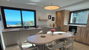 A modern kitchen with a large island, white cabinetry, and a view of the ocean.