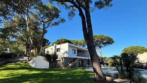 A modern two-story house with a stone facade, a visible staircase, and a well-maintained lawn.