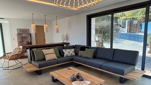 A modern living room with a sectional sofa, wooden coffee table, and pendant lights.