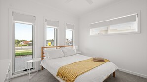 Ein Schlafzimmer mit einem Bett, zwei Nachttischen, einem Fenster und Blick ins Freie.