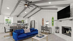 Ein modernes Wohnzimmer mit einem blauen Sofa, einem Couchtisch, einem Kamin und einem an der Wand montierten Fernseher.