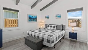 Ein Schlafzimmer mit einem Bett, einer Bank, einem Nachttisch und Kunstwerken an den Wänden.