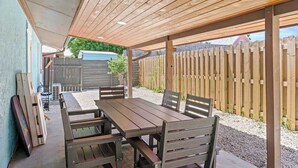 Eine Terrasse im Freien mit einem Holztisch und -bänken, umgeben von einem Holzzaun.