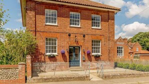 A two-story brick building with a tiled roof, a front door, and a small porch area with potted plants. - 5 Star Chapel In The Heart Of North Norfolk (Dereham)