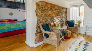 A cozy living room with a stone wall, wicker furniture, and a colorful rug. - 5 Star Chapel In The Heart Of North Norfolk (Dereham)