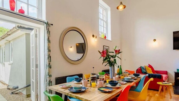 A dining area with a wooden table, colorful chairs, and a mirror on the wall. - 5 Star Chapel In The Heart Of North Norfolk (Dereham)