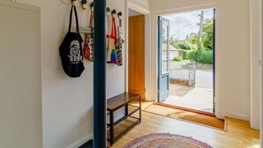 A modern interior with a bench, a wall-mounted bag rack, and a door leading to a garden. - 5 Star Chapel In The Heart Of North Norfolk (Dereham)